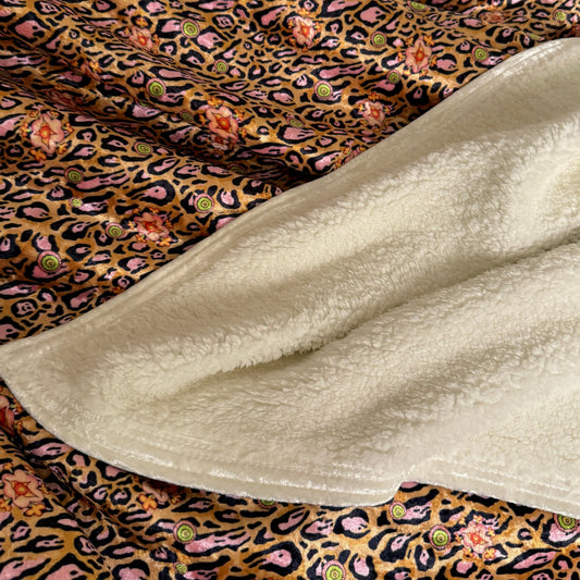 Folded blanket with leopard print and floral patterns on a white background